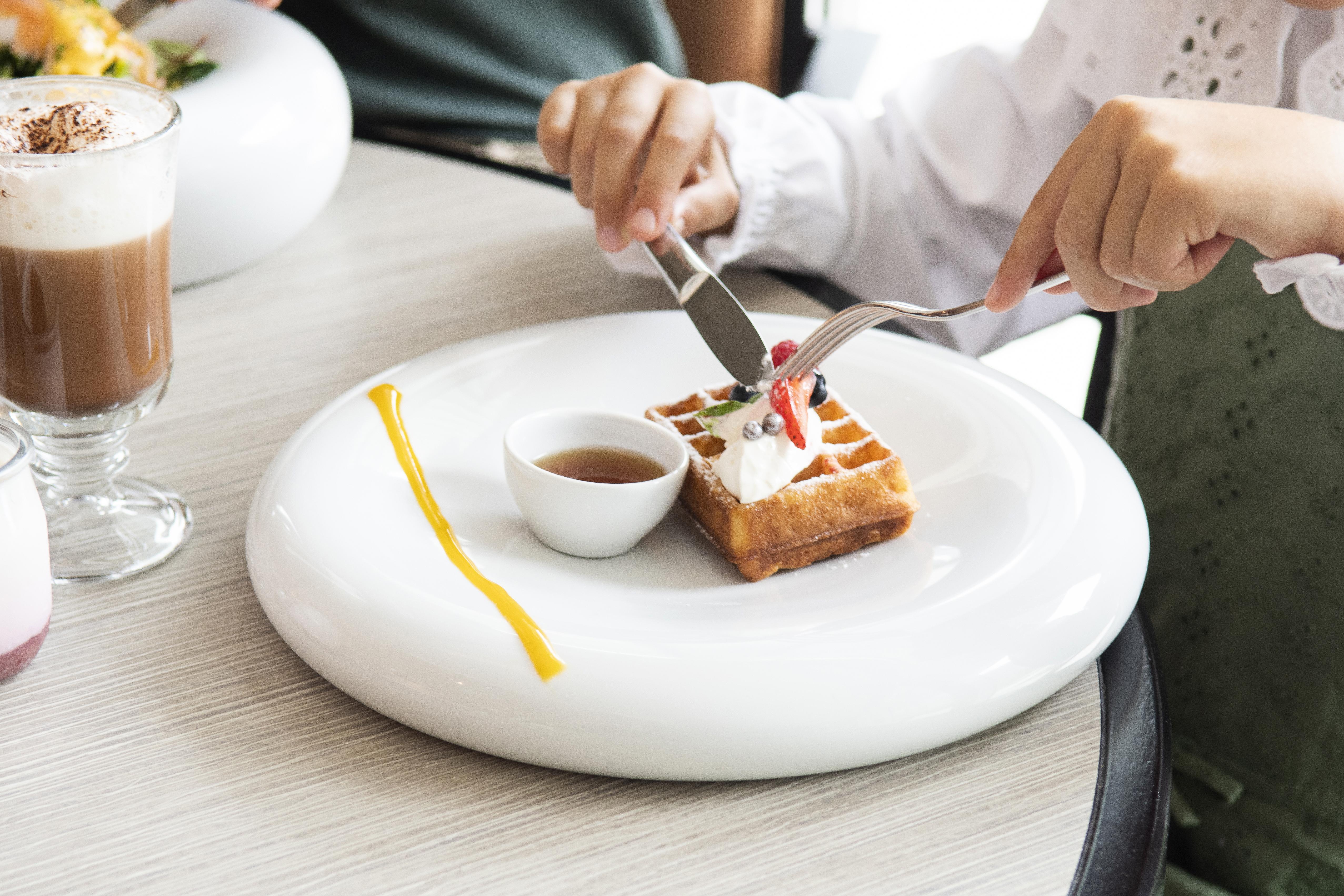 Epic Sana Lisboa Hotel Exterior foto A woman using a knife and fork to cut a dessert